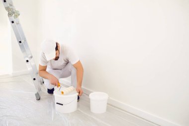 Beyaz üniformalı ev ressamı. Beyaz arka planda. Odada resim yapmak için..