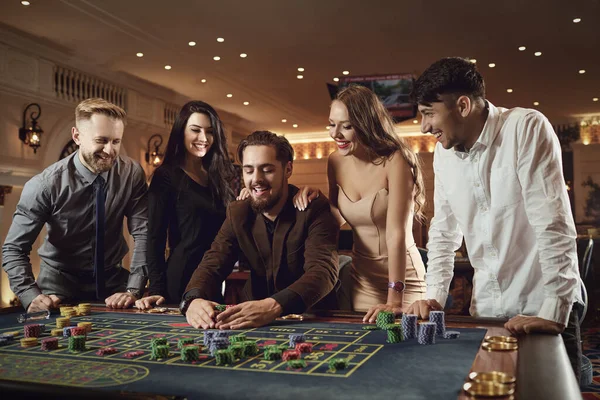 幸せな人々はカジノのルーレットポーカーでギャンブルに賭けています — ストック写真
