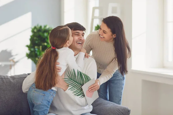 Fijne vaderdag. Moeder en kind dochter feliciteert vader met een ansichtkaart in een kamer met een raam. — Stockfoto