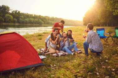 Young people make soap bubbles while sitting on the grass on in nature.