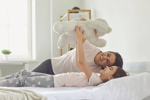 Feliz Dia das Mães. Mãe e filha estão abraçando enquanto deitado em uma cama em um interior casa branca . — Fotografia de Stock