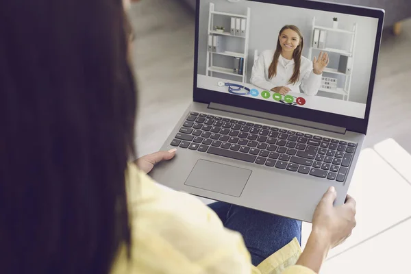 Arzt online. Eine Frau in legerer Kleidung lauscht einem Videoanruf, in dem sie vom Skype-Laptop zu Hause einen Arzt konsultiert.. — Stockfoto