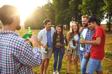 Young people drink and clink glasses at a picnic