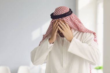 Arap adam üzgün, yorgun, bunalımlı, elleri kapalı, yüzünü kapatmış..