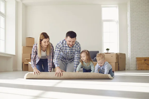 Ευτυχισμένη οικογένεια με χαλί στο πάτωμα σε ένα νέο διαμέρισμα. — Φωτογραφία Αρχείου