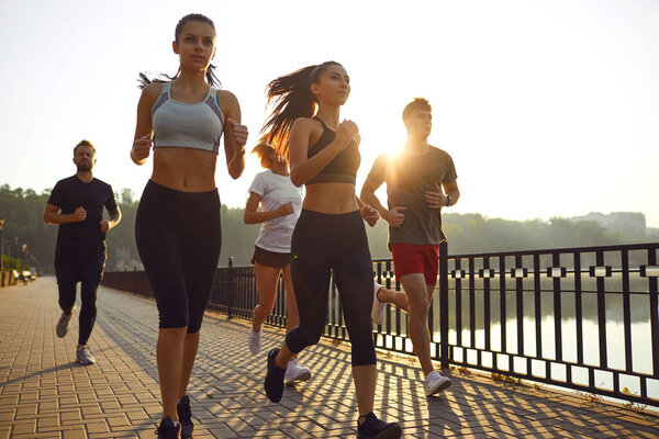 Группа молодых людей бежит в парке
.