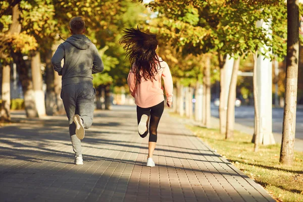 Un hombre y una mujer corren por la calle de la ciudad por la mañana. . — Foto de Stock