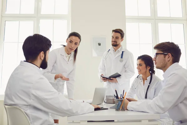 Grupo de médicos praticantes em uma reunião discutir o diagnóstico de um paciente de pé em um consultório de clínica . — Fotografia de Stock