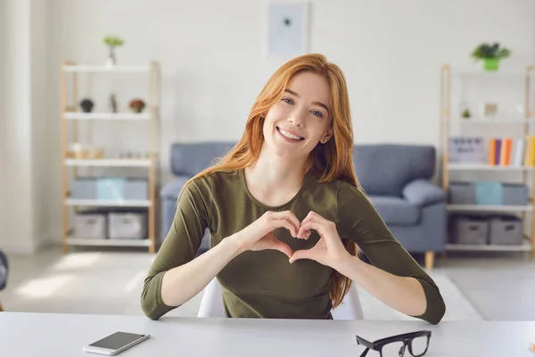 Delighted ginger woman gesturing heart in room. — Stock Photo, Image