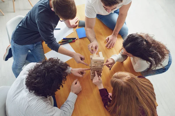 Les jeunes s'amusent à jouer à des jeux de société à une table dans la salle . — Photo