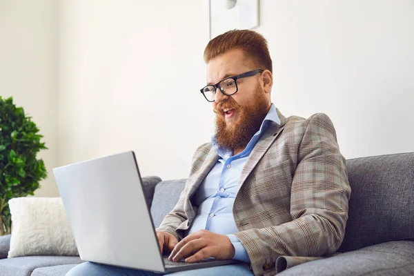 Pracuj online. Funny vousatý muž v brýlích smích pracovní on-line video chat volání pomocí notebooku doma kancelář. — Stock fotografie