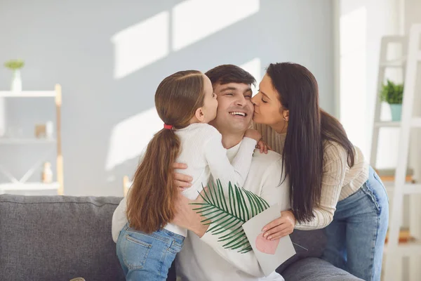 Fijne vaderdag. Moeder en kind dochter feliciteert vader met een ansichtkaart in een kamer met een raam. — Stockfoto