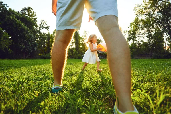 Padre juega con su hija en una tarve ball en un parque al atardecer . — Foto de Stock