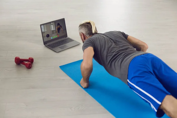Exercise at home online. Girl doing exercises on the floor watching a video course using a laptop in a living room at home. — Stock Photo, Image