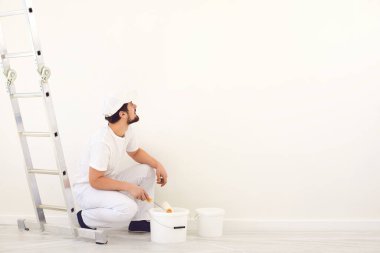 Beyaz üniformalı ev ressamı. Beyaz arka planda. Odada resim yapmak için..