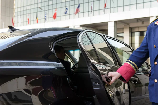 Швейцар открывает дверь роскошного автомобиля Стоковая Картинка