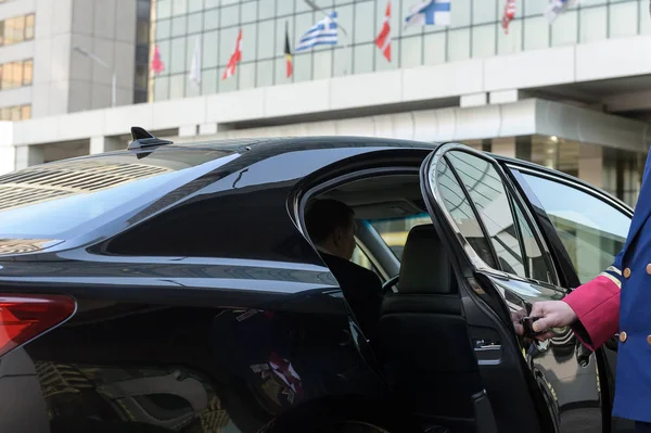 Швейцар открывает дверь роскошного автомобиля Стоковое Фото
