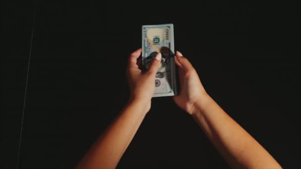 Las manos de la mujer toman y muestran un fan de billetes de dólar en el fondo negro — Vídeo de stock