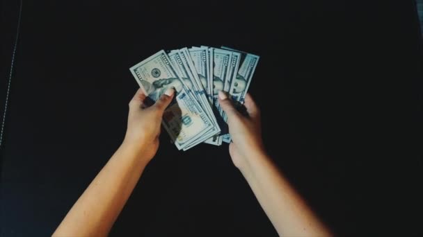 Χέρια γυναίκα δείχνει ένας ανεμιστήρας των λογαριασμών του δολαρίου στο μαύρο υπόβαθρο — Αρχείο Βίντεο