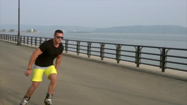 Jeune homme sportif avec des patins à roues alignées rouler en été front de mer — Video