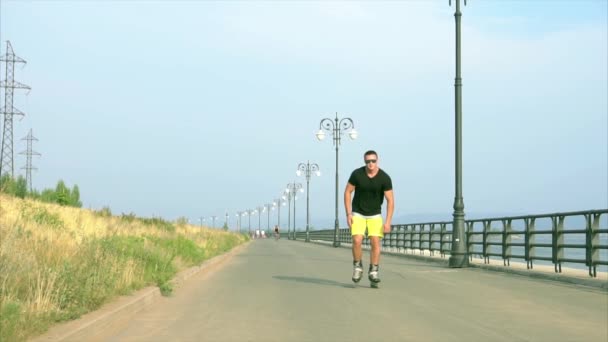 Sportieve jongeman rolschaatsen aan zomer waterkant — Stockvideo