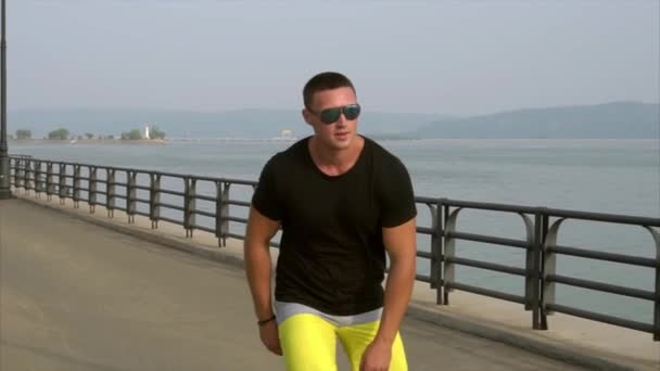 Ung sportig man med inlines rida i sommar waterfront — Stockvideo