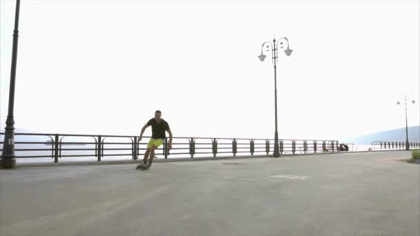 Молодой спортсмен катается на роликовых коньках на летней набережной — стоковое видео