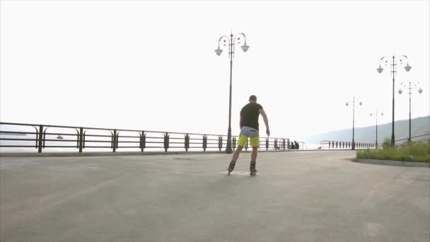 Młody człowiek sportowy uczy się rolki na nabrzeżu — Wideo stockowe
