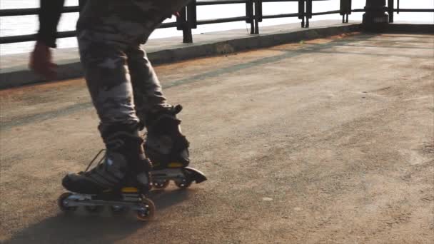 Mans benen rolschaatsen-inline close-up op de asfalt-zonsondergang — Stockvideo