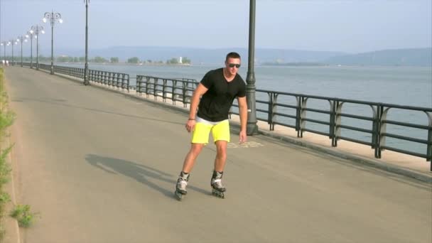 Hombre joven deportivo patinaje sobre ruedas en el paseo marítimo de verano — Vídeo de stock