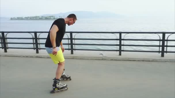Young sporty man roller skating on summer seafront — Stock Video
