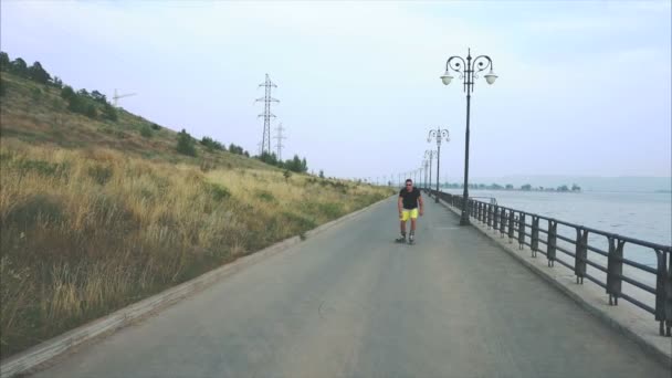 Junger sportlicher Mann beim Rollschuhlaufen am sommerlichen Ufer — Stockvideo