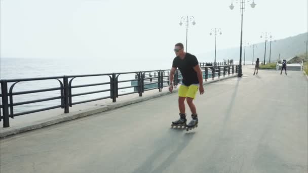 Hombre joven deportivo patinaje sobre ruedas en el paseo marítimo de verano — Vídeos de Stock