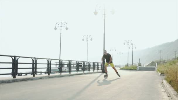 Молодой спортсмен катается на роликах на летней набережной — стоковое видео