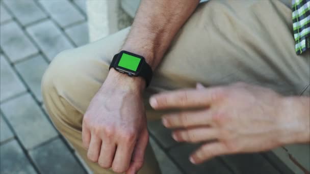 Ο άνθρωπος στα χέρια χειρονομίες ένα σύγχρονο έξυπνο ρολόι με ένα περιεχόμενο chroma-κλειδί πράσινη οθόνη — Αρχείο Βίντεο