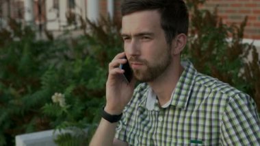 Laughting konuşmak ve onun arkadaşı ile cep telefonuyla gülümseyen genç adam