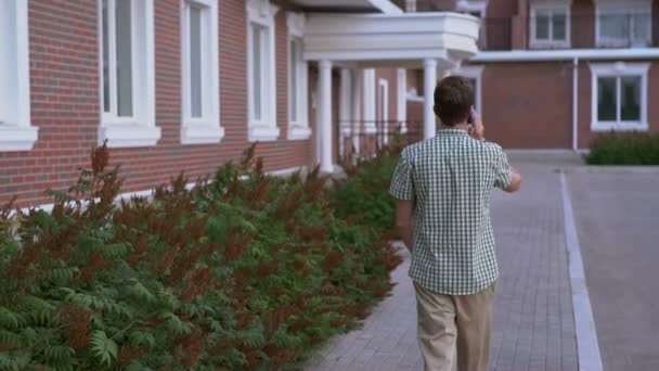 Lässig gekleideter Mann läuft auf die Straße und spricht per Smartphone-Zeitlupe — Stockvideo