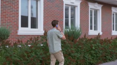 Casual giyimli adam giyen smartwatch sokakta dolaşıp smartphone ile konuşmak