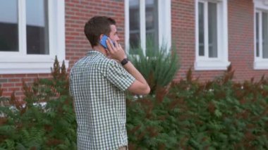 Casual giyimli adam giyen smartwatch sokakta dolaşıp smartphone ile konuşmak