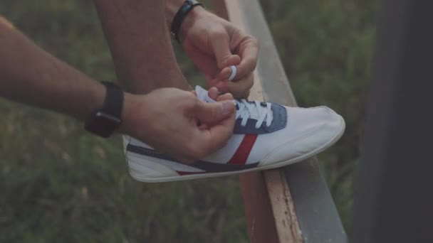 Человек бегун завязывая шнурки в природе — стоковое видео
