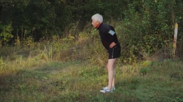 Oude man senior doet ochtend warming-up oefeningen vóór het joggen — Stockvideo