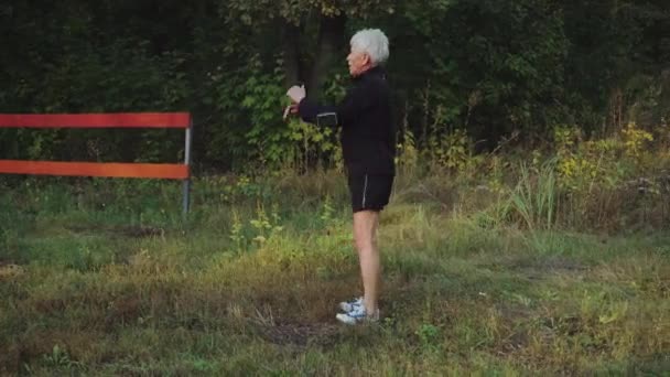 Viejo hombre mayor hace ejercicios de calentamiento por la mañana antes de correr — Vídeos de Stock
