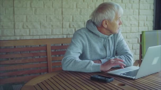 Senior man surfing on internet outside the house sitting on the porch — Stock Video