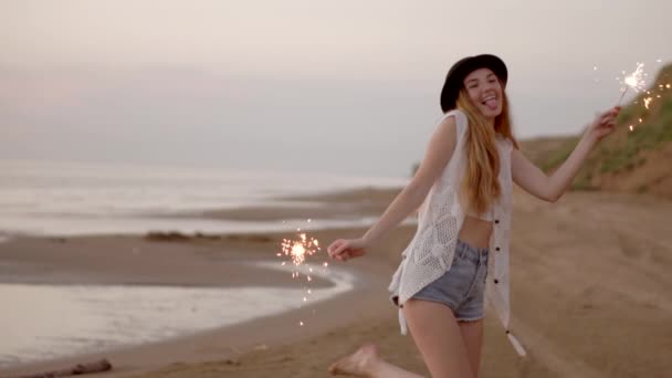 Teenager schöne Mädchen mit Wunderkerzen am Strand bei Sonnenuntergang — Stockvideo