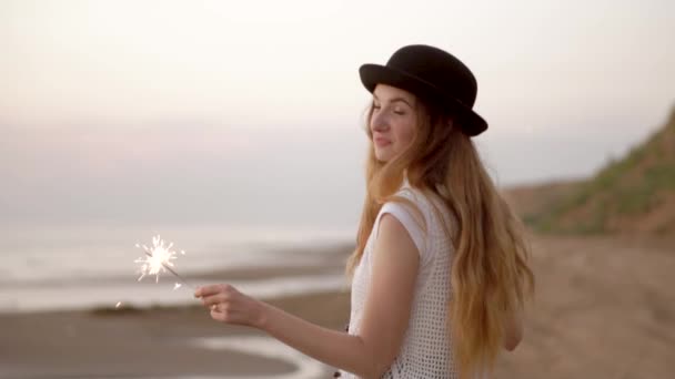 Adolescente belle fille avec des étincelles sur la plage au coucher du soleil — Video