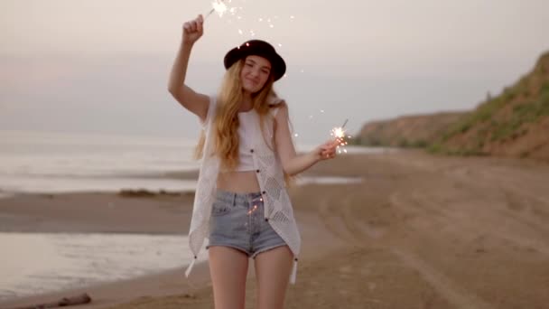 Adolescente menina bonita com faíscas na praia ao pôr do sol — Vídeo de Stock