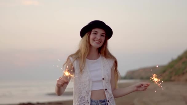 Adolescente hermosa chica con chispas en la playa al atardecer — Vídeo de stock