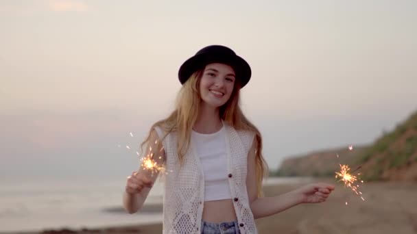 Adolescente menina bonita com faíscas na praia ao pôr do sol — Vídeo de Stock