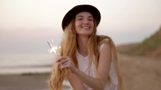 Adolescente menina bonita com faíscas na praia ao pôr do sol — Vídeo de Stock