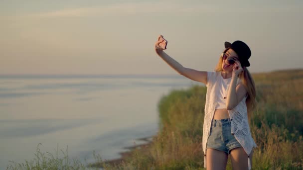 Junge Frau macht Selfie am Rande einer Klippe in der Nähe des Flusses — Stockvideo
